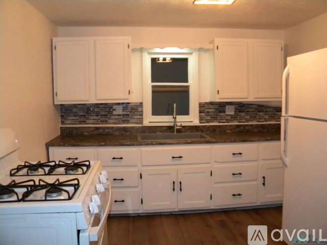 A kitchen with white cabinets and a black countertop.