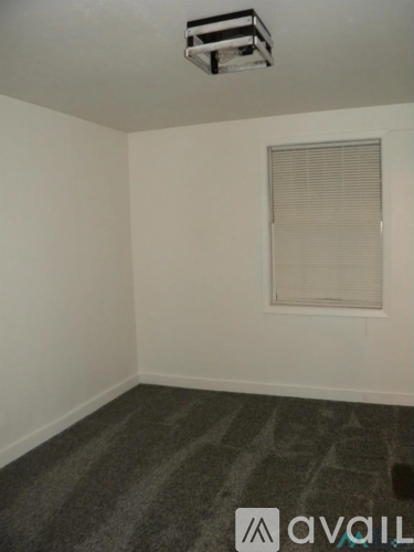 A room with a carpeted floor and a window with blinds.