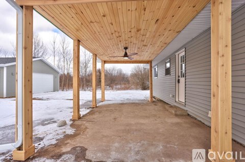 A wooden porch with a ceiling fan and a door is available for rent.