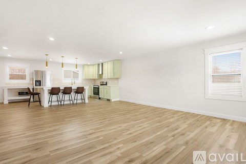 A spacious room with wooden flooring and a kitchen area with a sink and stove.