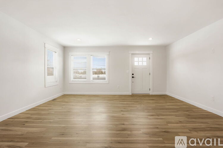 A spacious room with wooden flooring and white walls.