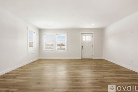 A spacious room with wooden flooring and white walls.