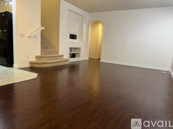 A spacious room with a staircase and a doorway leading to another room.