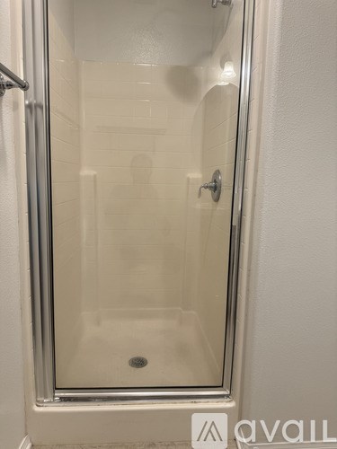 A glass shower door with a handle and a drain.