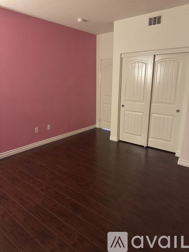 A room with a pink wall and a white door.