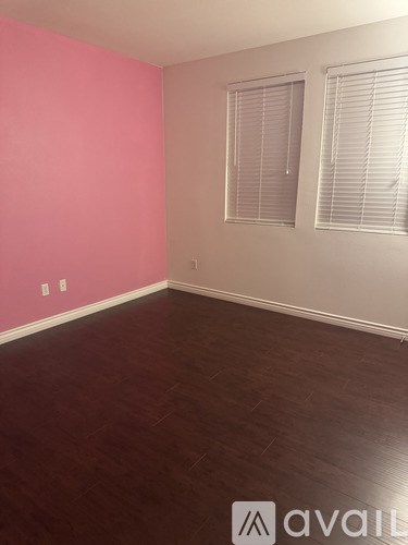 A room with a pink wall and a window with blinds.