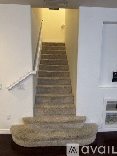 A staircase with a carpeted runner and a white wall on the side.