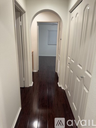 A hallway with wood floors and white walls.