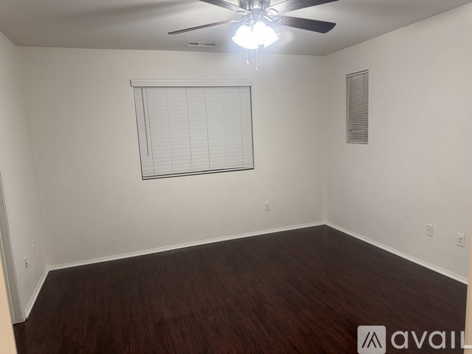 A room with a ceiling fan and a window with blinds.