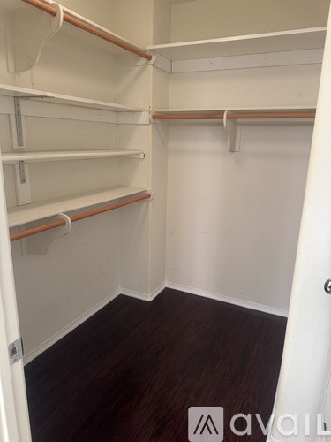 Empty walk-in closet with white shelves and wooden floors.
