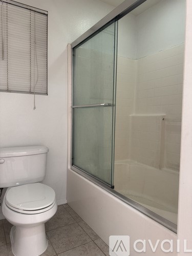 A white toilet sits next to a glass shower door in a bathroom.