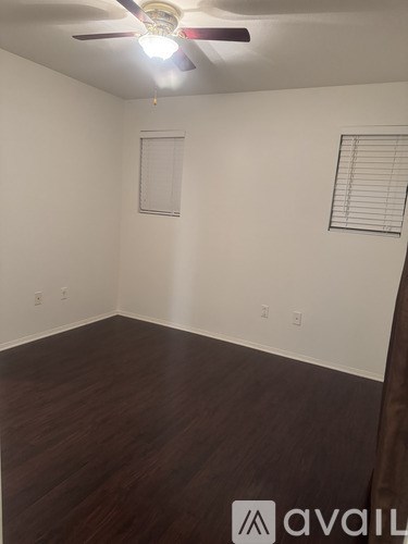 A room with a ceiling fan and wooden flooring.