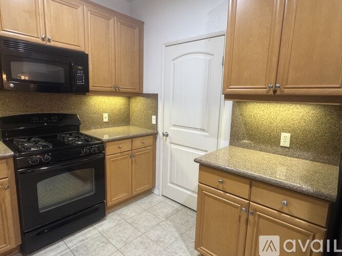 A kitchen with wooden cabinets and a black stove top oven.