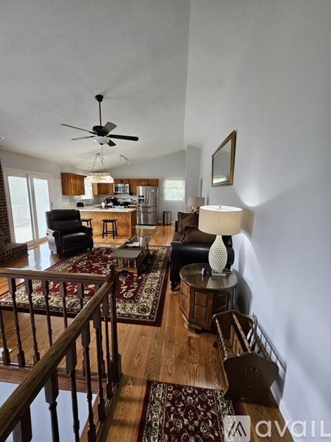 A living room with a rug on the floor and a fan on the ceiling.