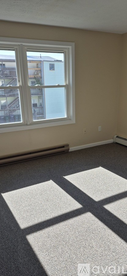 A room with a window and a carpet with a white square on it.