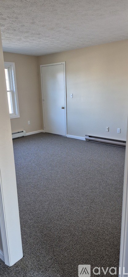 A room with a carpeted floor and a door.