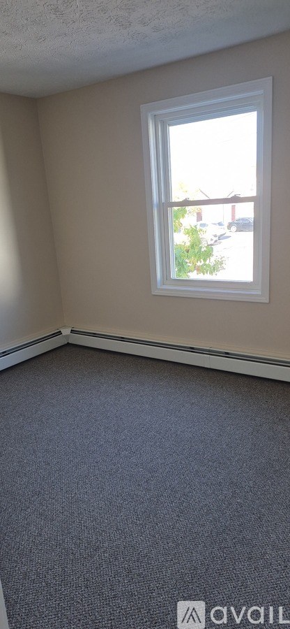A room with a window and carpeted floor.
