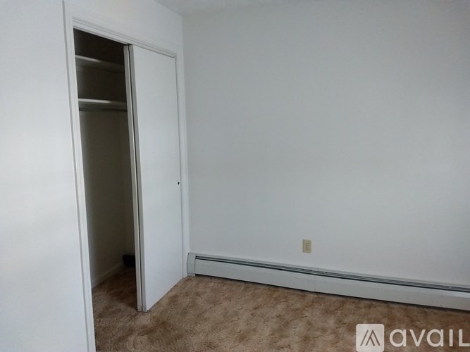 A room with a carpeted floor and a wall-mounted air conditioner unit.