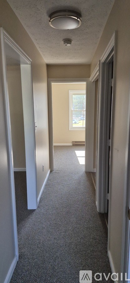 A long hallway with a carpeted floor and white walls.