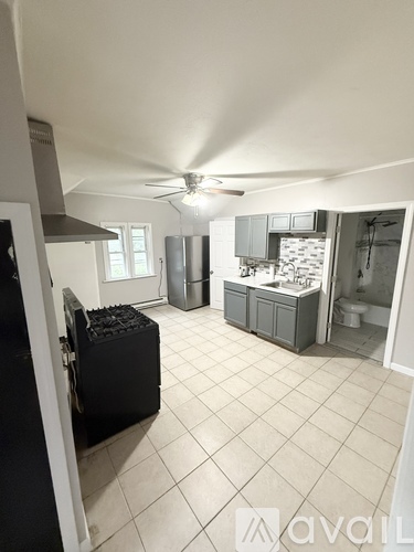A kitchen with grey cabinets and a marble backsplash.