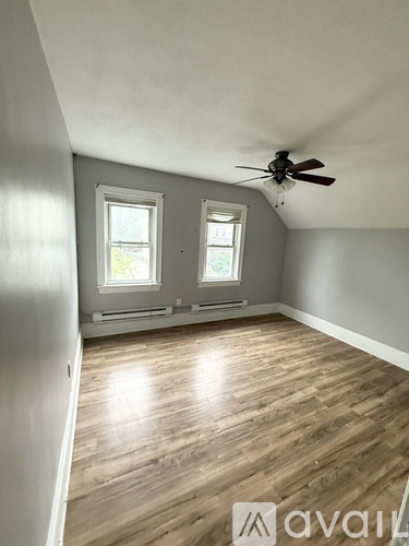 A room with a ceiling fan and wooden flooring.