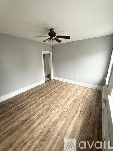A room with wooden flooring and a ceiling fan.