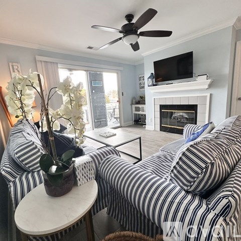 A living room with a striped couch and a television on the wall.