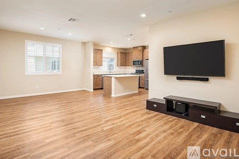 A spacious living room with a television and a wooden floor.