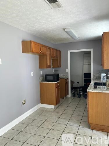 A kitchen with wooden cabinets and a tiled floor.