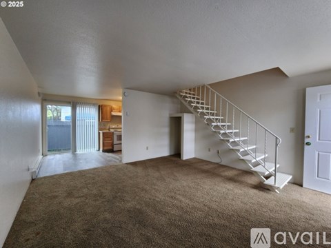 A spacious room with a staircase leading to another floor.