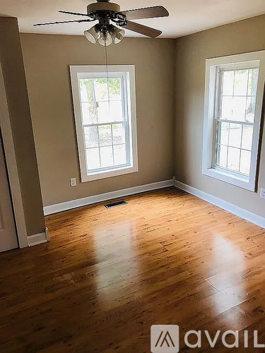 A room with wooden floors and two windows.