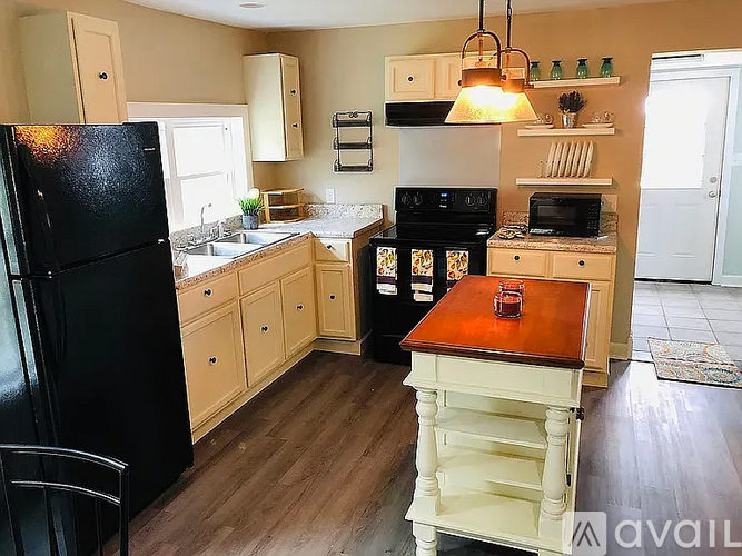 A kitchen with black appliances and wooden floors.