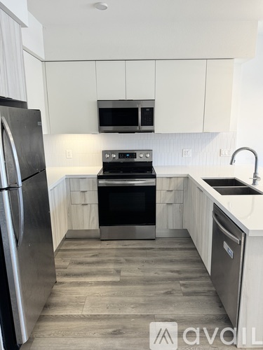 A kitchen with a stainless steel refrigerator and a stove top oven.