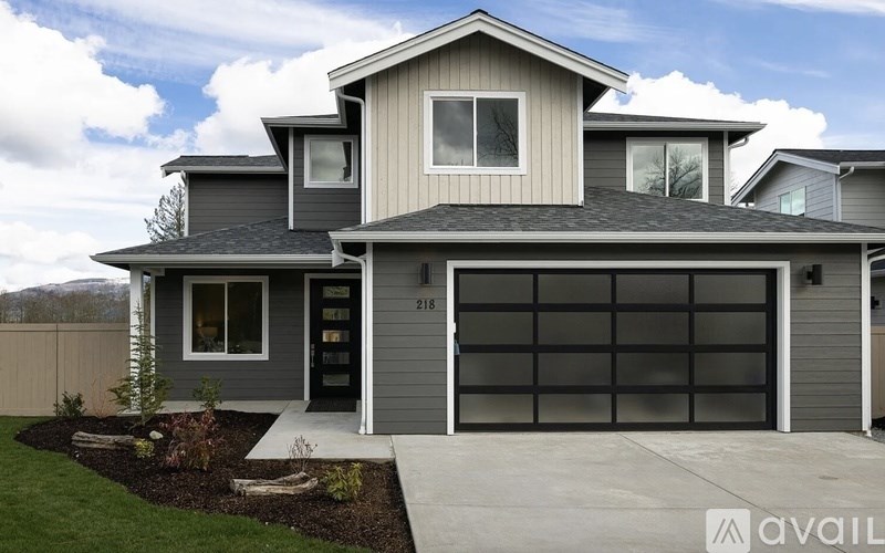 A modern house with a grey garage door is for sale.