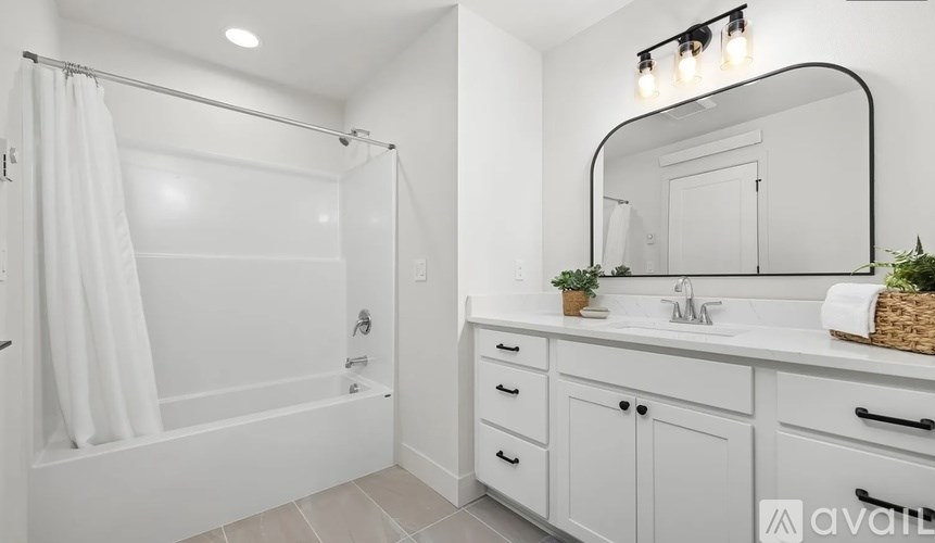 A white bathroom with a white tub, sink, and mirror.