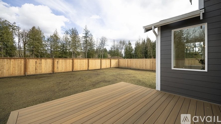 A wooden deck with a house and trees in the background.