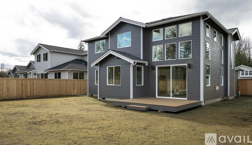 A modern house with a grey exterior and large windows is for sale.