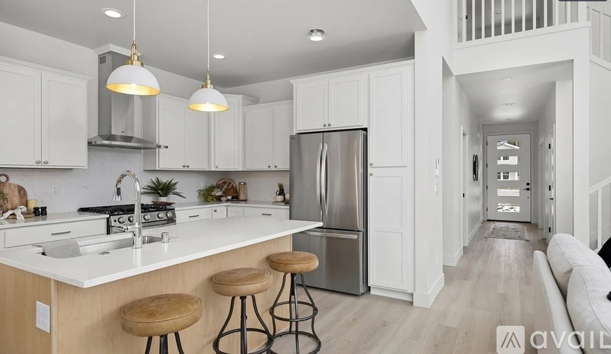 A kitchen with white cabinets and a stainless steel refrigerator.