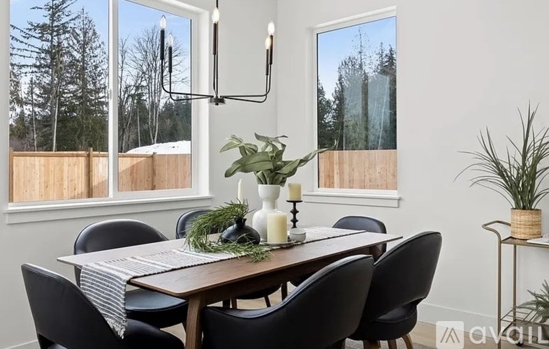 A dining room with a wooden table and chairs, a candle, and a plant on the table.