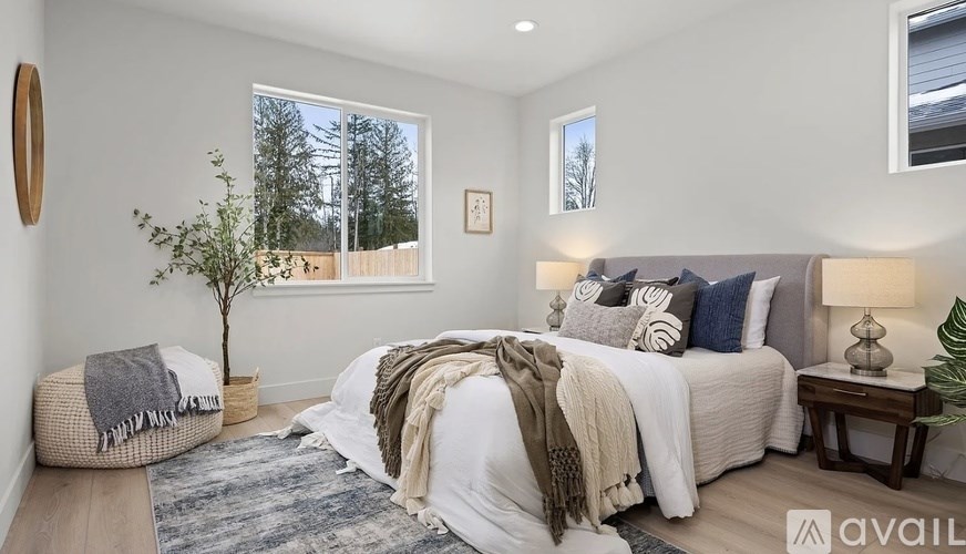 A bedroom with a large bed and a view of trees outside the window.