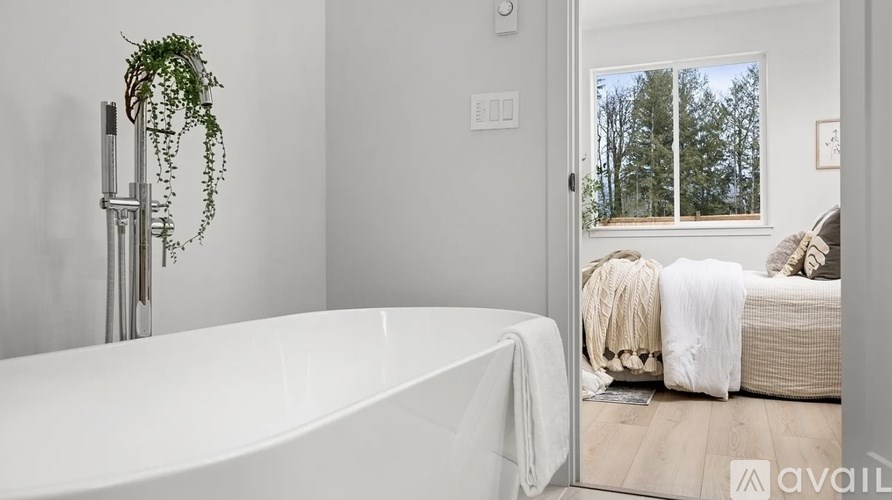 A bathroom with a white tub and a window showing trees outside.