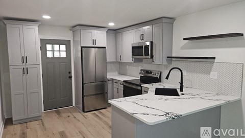 A kitchen with a refrigerator, microwave, and cabinets.