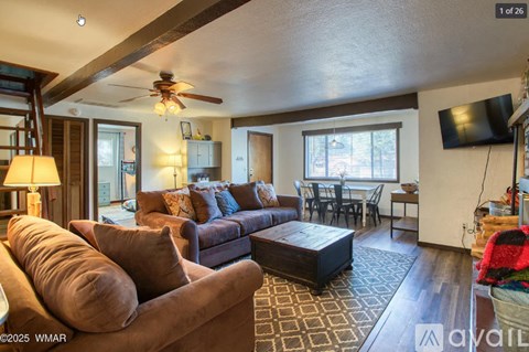 A living room with a brown couch and a ceiling fan.