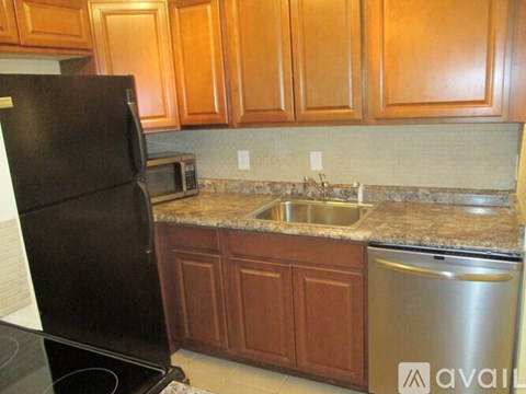 A kitchen with brown cabinets and a black refrigerator.