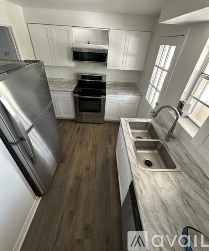 A kitchen with a stainless steel refrigerator and a sink with a marble countertop.