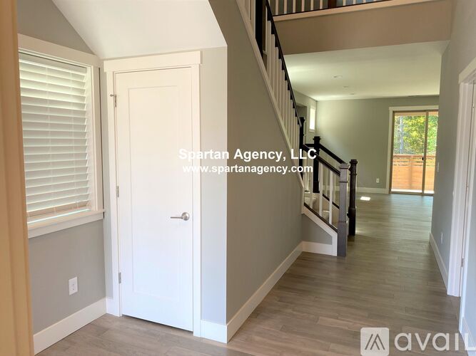 A hallway with a staircase and a door on the left side.