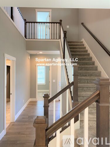 A staircase with a wooden handrail and a balcony with a glass door.
