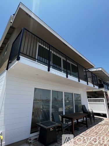 A balcony with a table and chairs is on the second floor of a house.
