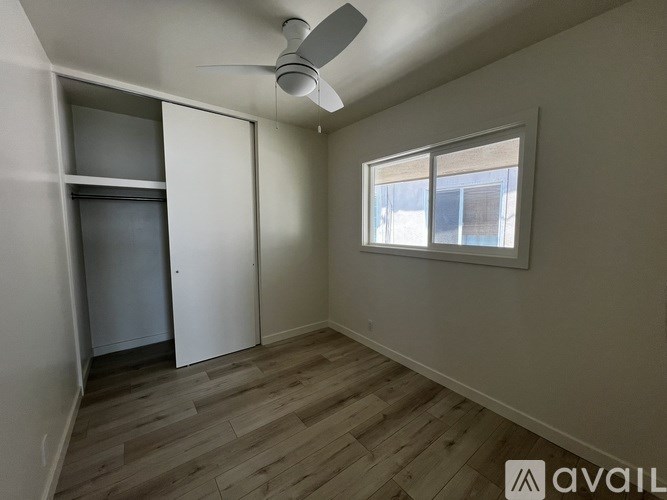 A room with a ceiling fan and a window with blinds.