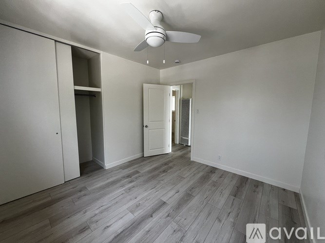 A room with a ceiling fan and wooden flooring.